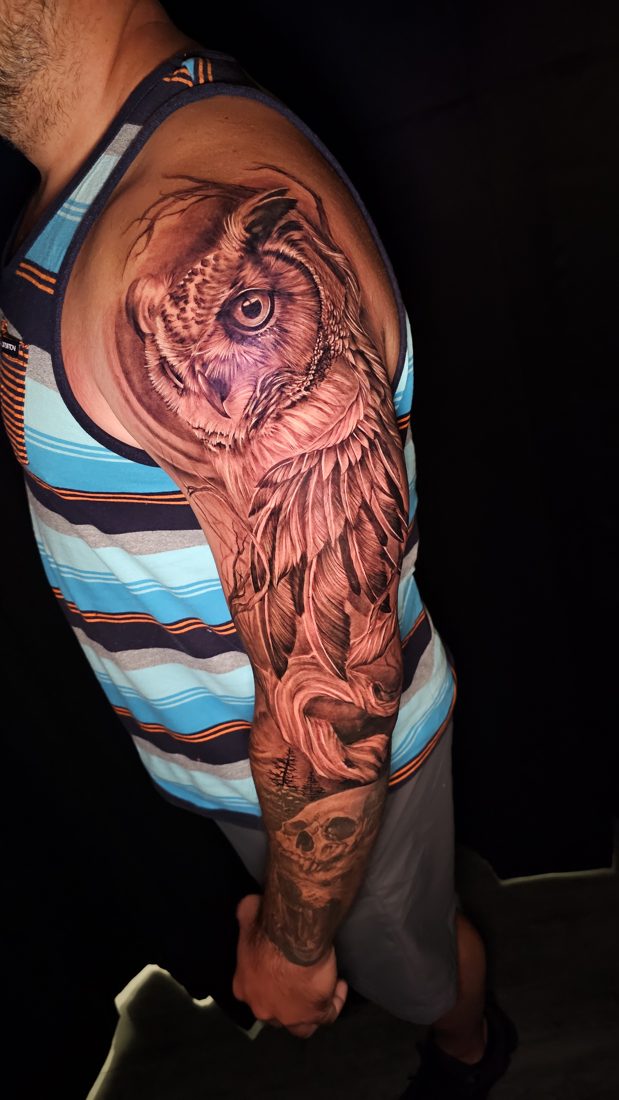 Owl in black and grey, tattoo on an upper arm